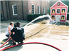 Firefighter Helping Kid Use Fire Hose