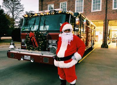 Person in Santa Costume in Front of Decorated Fire Truck